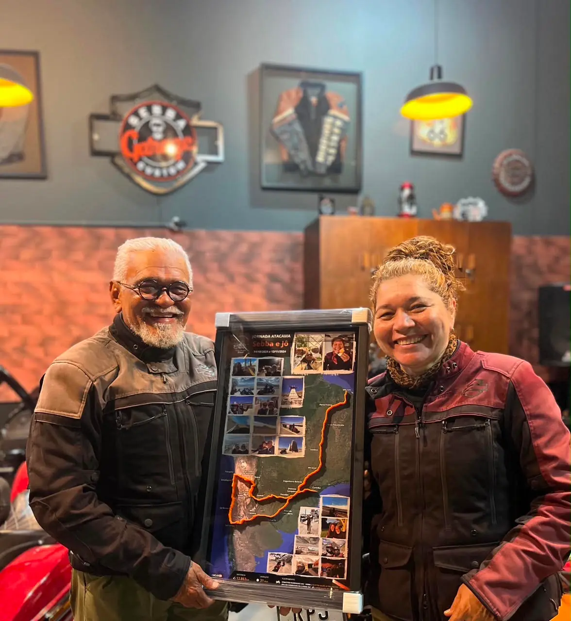 Joelma e Sebastião segurando o quadro da Jornada Atacama com o mapa da rota completa