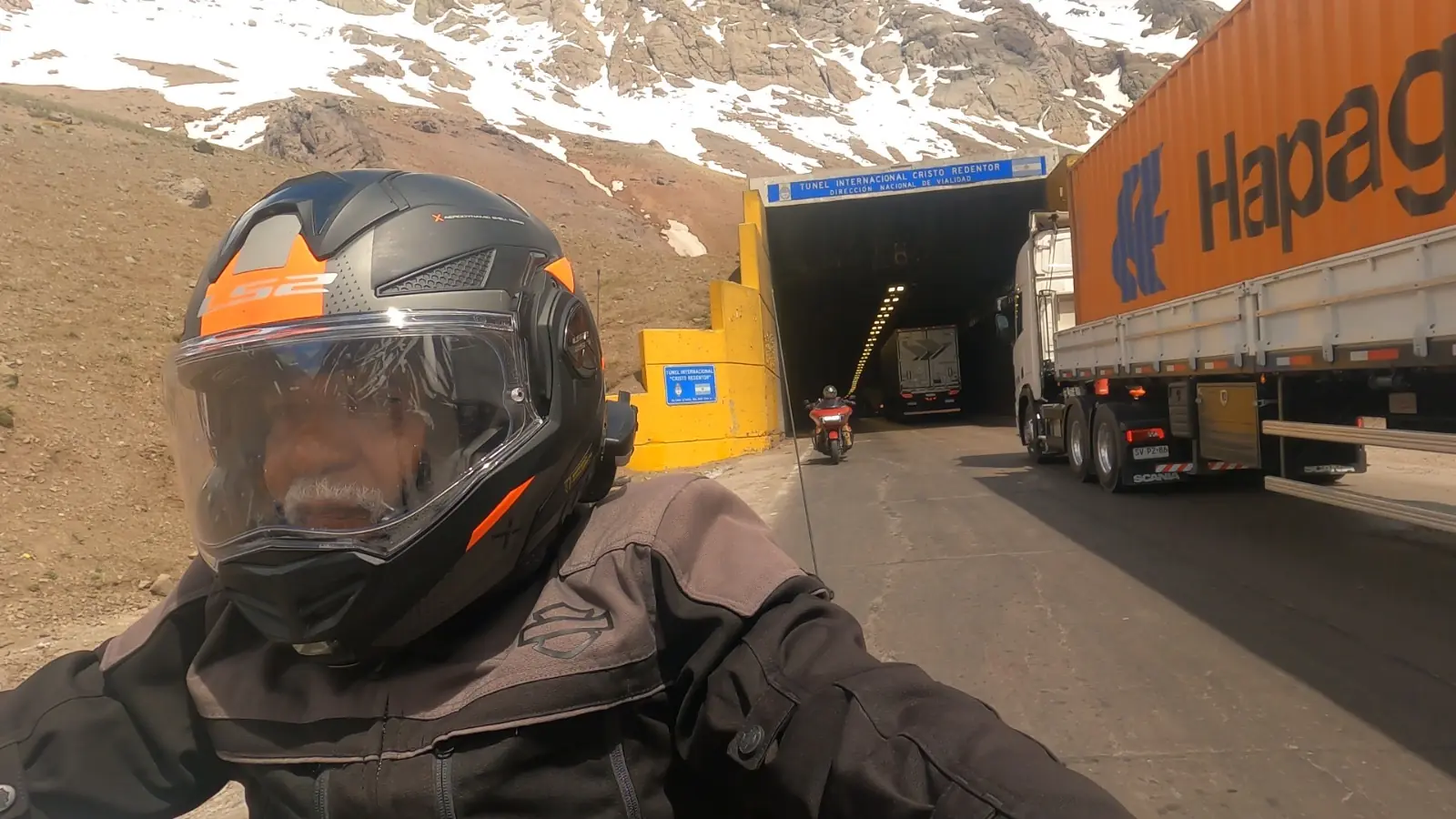 Sebastião de capacete na entrada do Túnel Internacional Cristo Redentor, com montanhas nevadas ao fundo